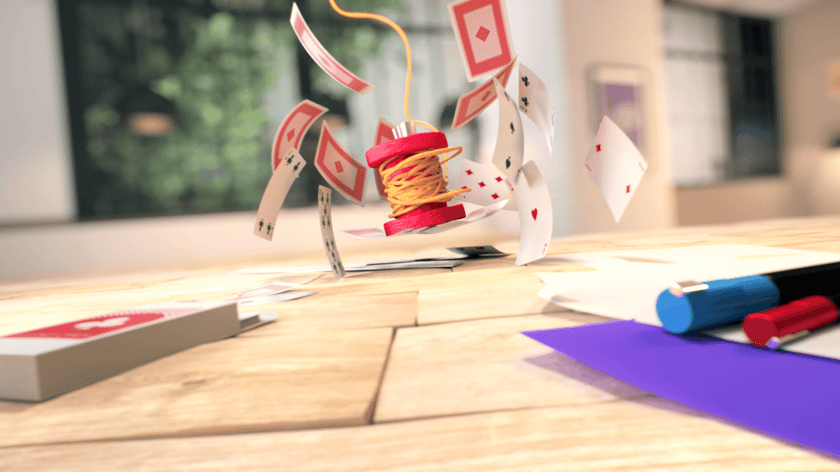 Spool of 3D plasticine thread falling on a deck of playing cards