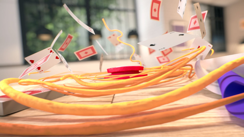 Spool of 3D plasticine thread falling on a deck of playing cards
